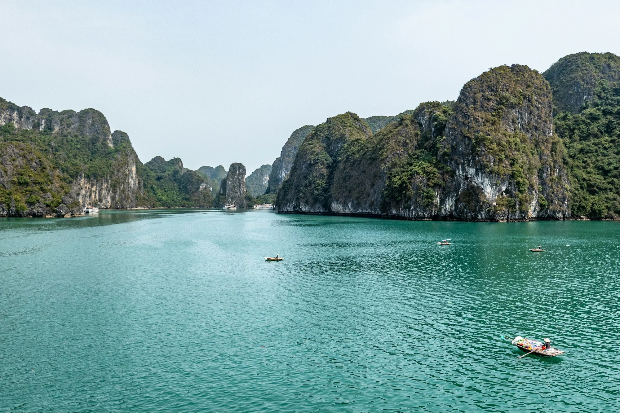 A luxury cruise boat sailing the bright, calm waters of Ha Long Bay